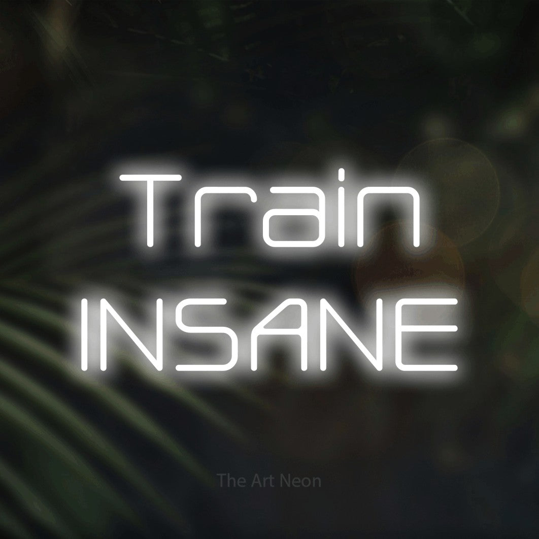 Cool white LED neon sign reading "Train Insane" against dark blurred palm leaves for gym décor