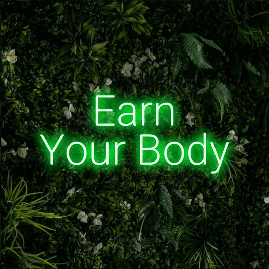 Green LED neon sign reading "Earn Your Body" against a leafy green wall for gym décor
