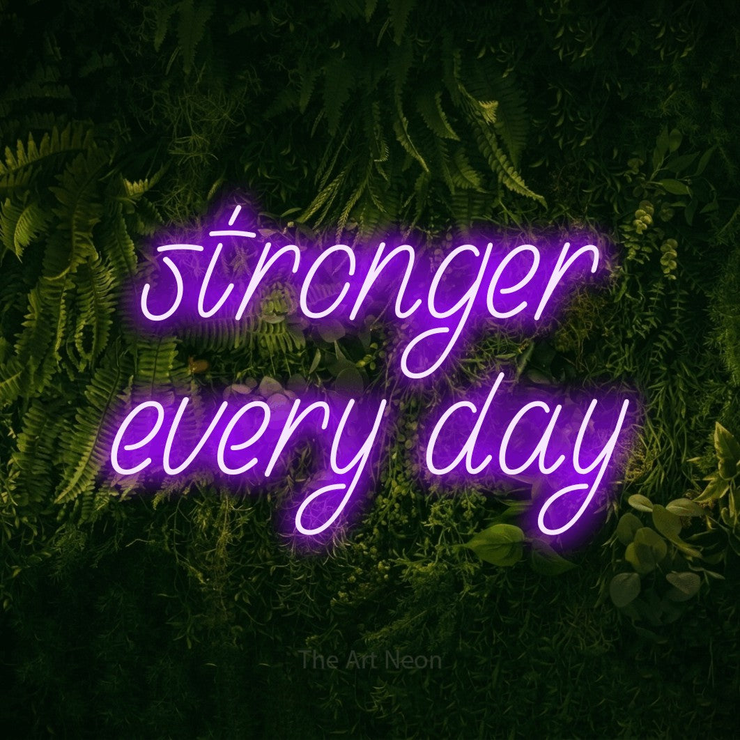 Purple LED neon sign reading "Stronger Every Day" against a moss-covered green wall for gym décor