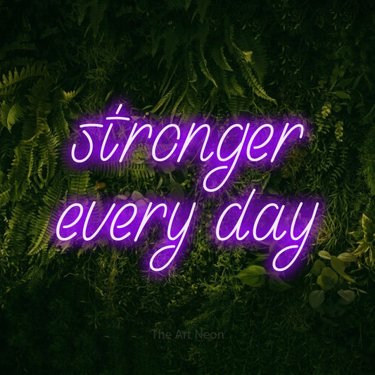 Purple LED neon sign reading "Stronger Every Day" against a moss-covered green wall for gym décor