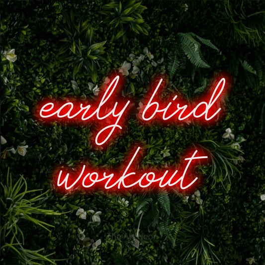 Red script-style LED neon sign reading "Early Bird Workout" against a leafy green wall for gym décor