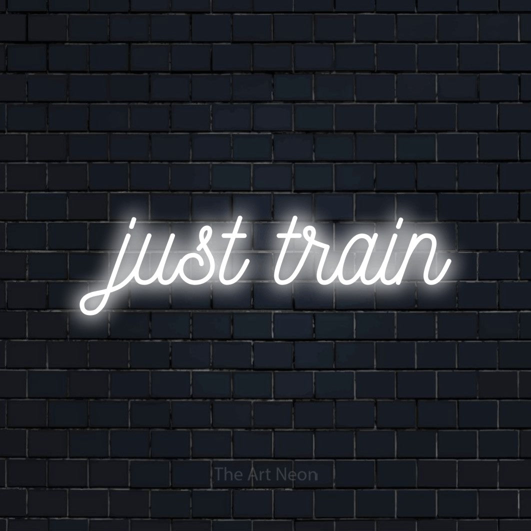 Enseigne néon à DEL à lumière blanche froide, de style manuscrit, affichant « Just Train » sur un mur de briques bleu marine foncé, pour décorer une salle d’entraînement