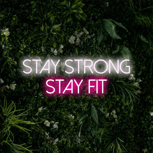 Hot pink and cool white LED neon sign reading "Stay Strong Stay Fit" against a leafy green wall for gym décor