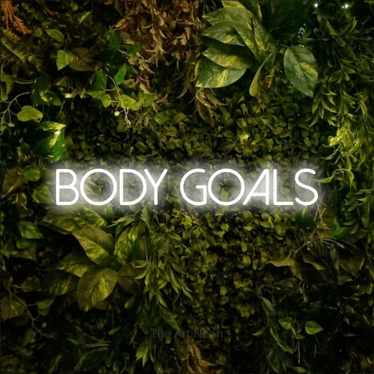 Cool white LED neon sign reading "Body Goals" against a textured moss and foliage wall for gym décor