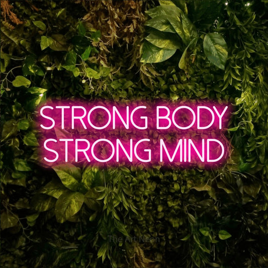 Hot pink LED neon sign reading "Strong Body Strong Mind" against a textured moss and foliage wall for gym décor