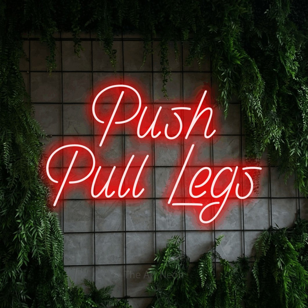 Red LED neon sign reading "Push Pull Legs" against a green grid wall with foliage for gym décor