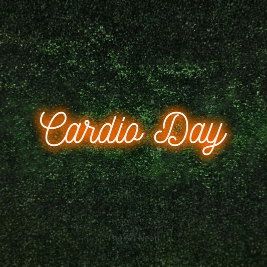 Enseigne néon à DEL à lumière orange, de style manuscrit, affichant « Cardio Day » sur un mur texturé de mousse verte, pour décorer une salle d’entraînement