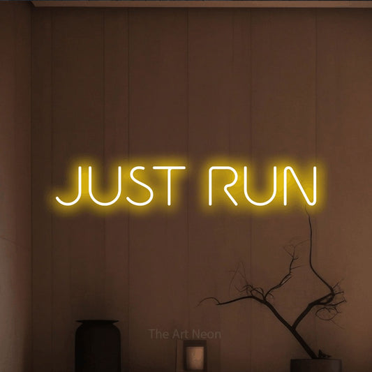 Enseigne néon à DEL à lumière jaune, affichant « Just Run » sur un mur brun chaleureux, pour décorer une salle d’entraînement