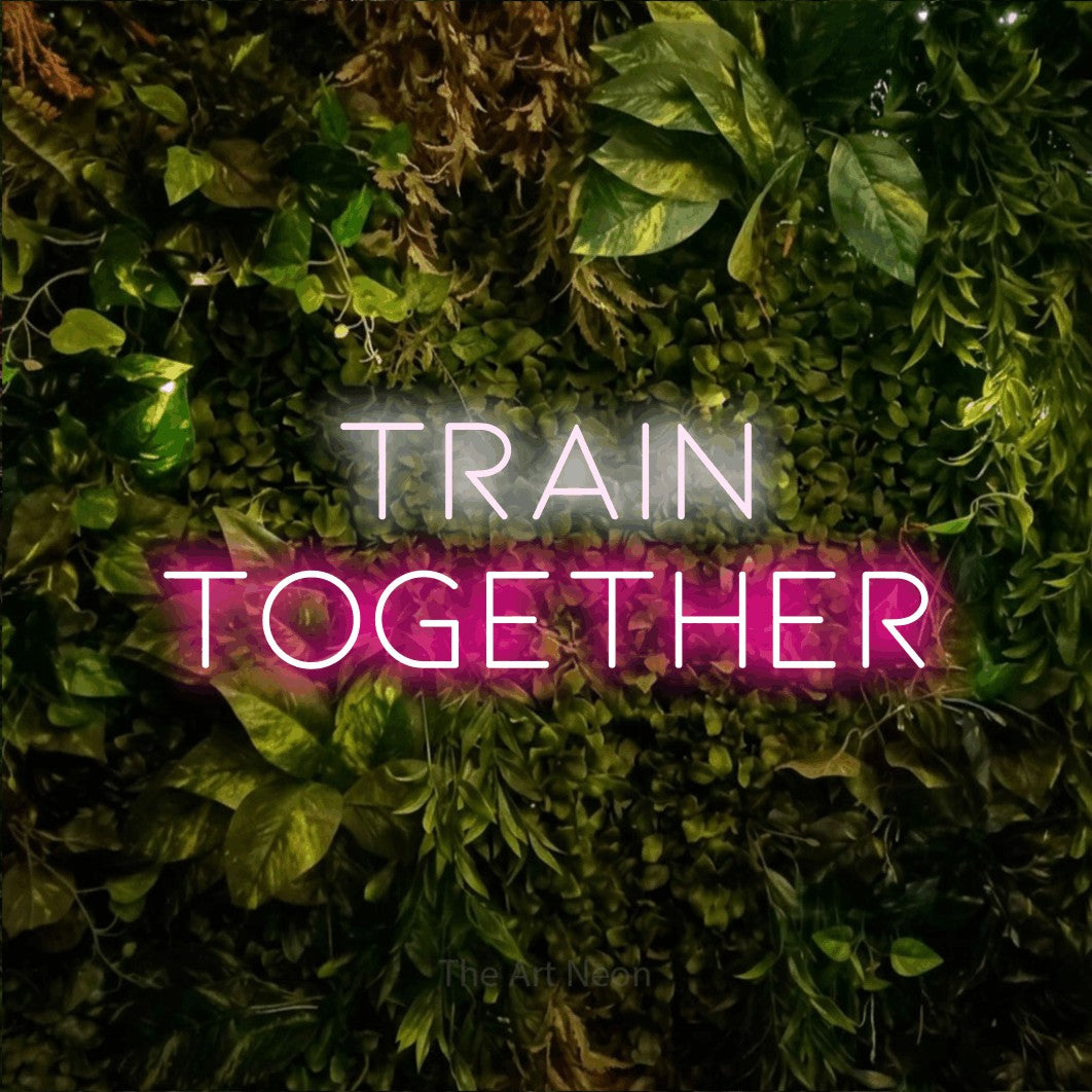 Enseigne néon à DEL à lumière rose vif et blanche froide, affichant « Train Together » sur un mur texturé de mousse et de feuillage, pour décorer une salle d’entraînement