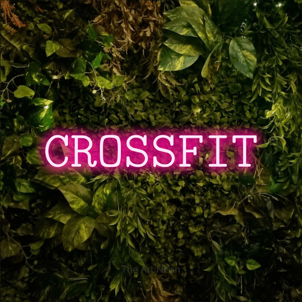 Enseigne néon à DEL à lumière rose vif, affichant « CrossFit » sur un mur texturé de mousse et de feuillage, pour décorer une salle d’entraînement