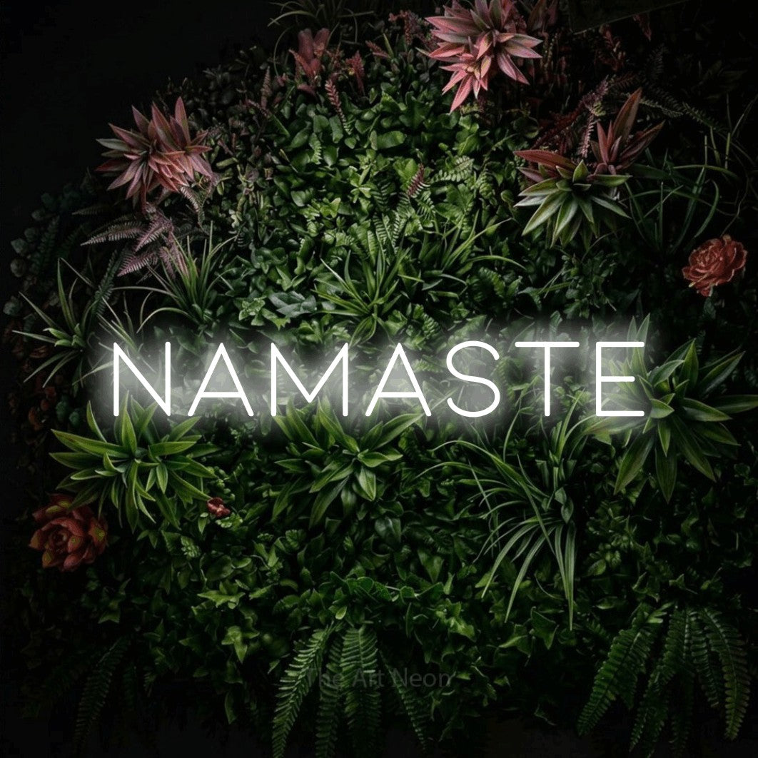 Enseigne néon à DEL à lumière blanche froide, affichant « Namaste » sur un mur de jardin fleuri, pour décorer une salle d’entraînement