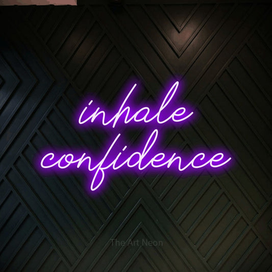 Purple script-style LED neon sign reading "Inhale Confidence" against a dark geometric wood wall for gym décor