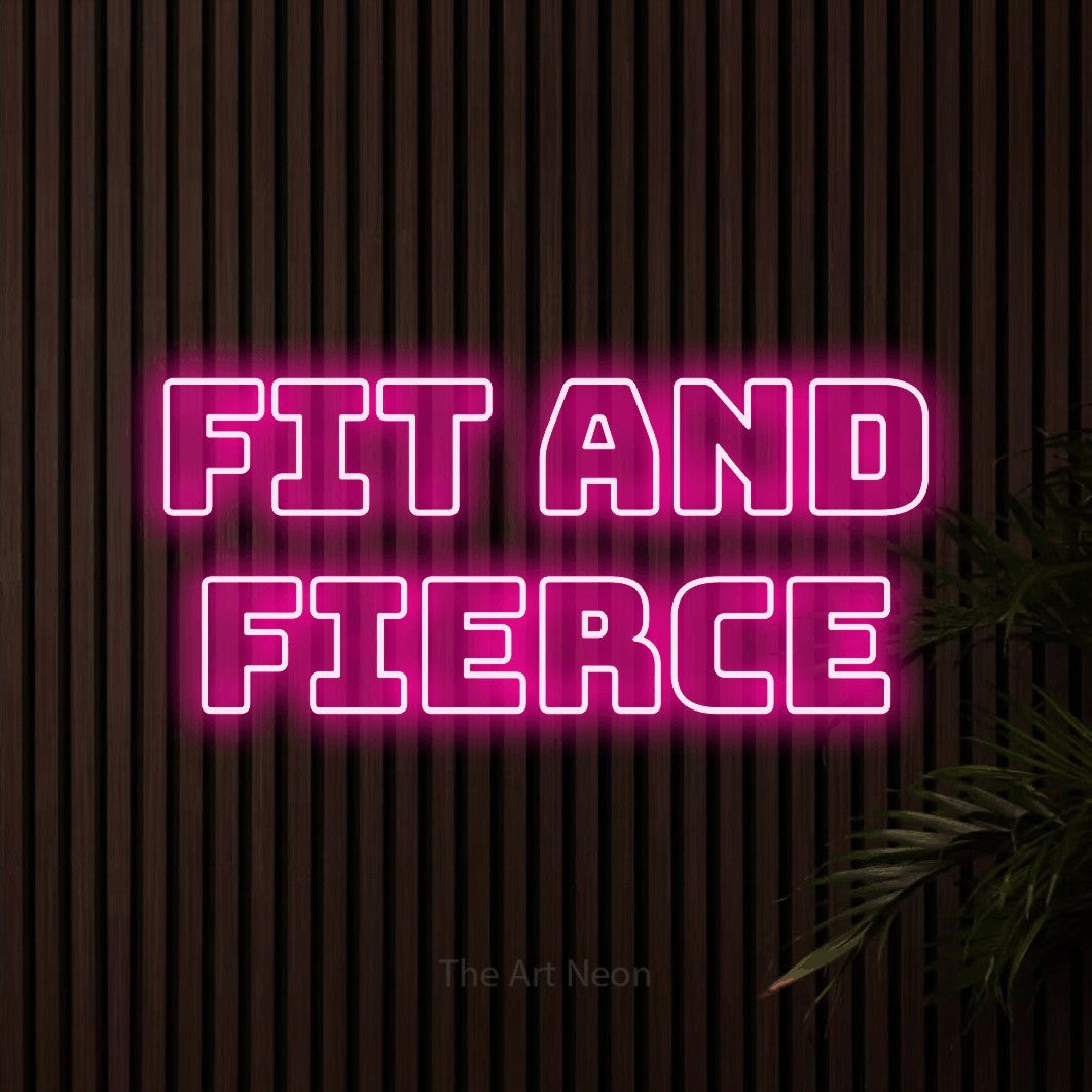 Hot pink outline-style LED neon sign reading "Fit and Fierce" against dark wooden slats for gym décor