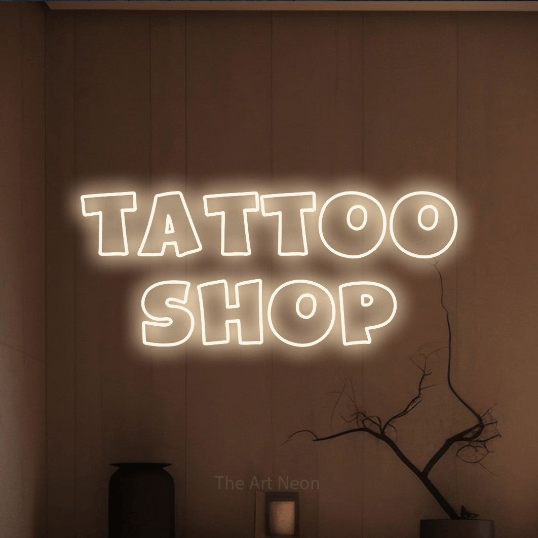 Warm white outline-style LED neon sign reading "Tattoo Shop" against a warm brown wall for tattoo studio décor