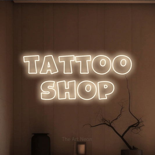 Warm white outline-style LED neon sign reading "Tattoo Shop" against a warm brown wall for tattoo studio décor