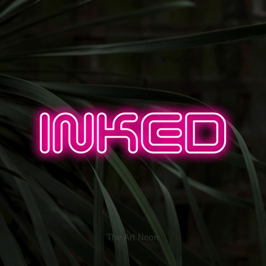 Hot pink outline-style LED neon sign reading "Inked" against dark tropical leaves for tattoo studio décor