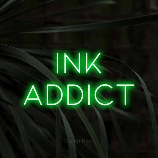 Green LED neon sign reading "Ink Addict" against dark tropical leaves for tattoo studio décor