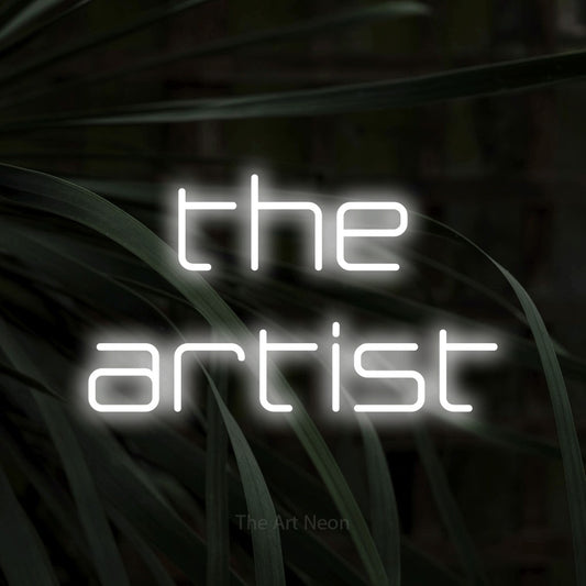 Cool white LED neon sign reading "The Artist" against dark tropical leaves for tattoo studio décor