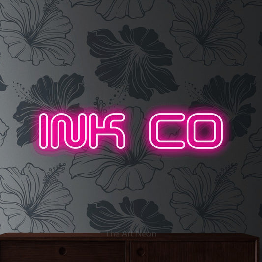Hot pink outline-style LED neon sign reading "Ink Co" against grey floral wallpaper for tattoo studio décor