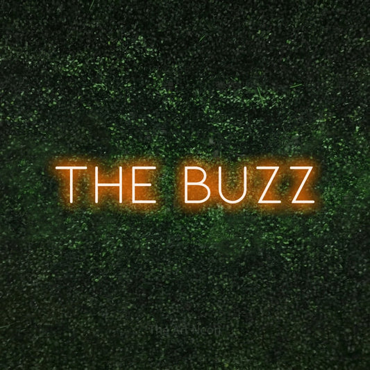Orange LED neon sign reading "The Buzz" against a textured green moss wall for tattoo studio décor