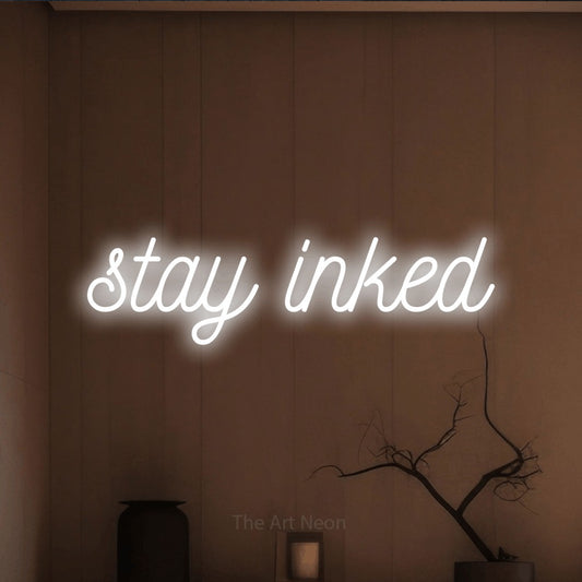 Cool white script-style LED neon sign reading "Stay Inked" against a warm brown wall for tattoo studio décor