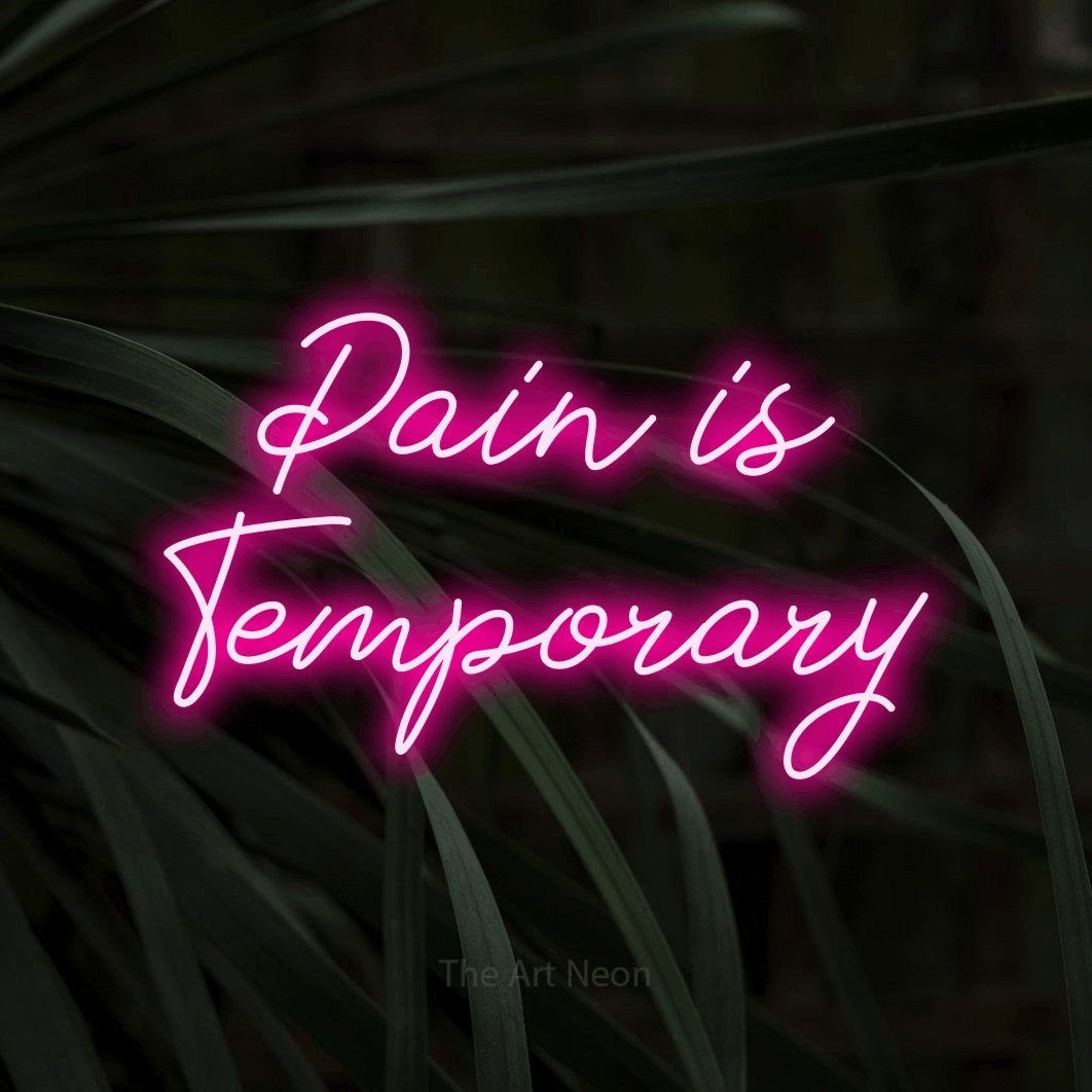 Hot pink script-style LED neon sign reading "Pain is Temporary" against dark tropical leaves for tattoo studio décor