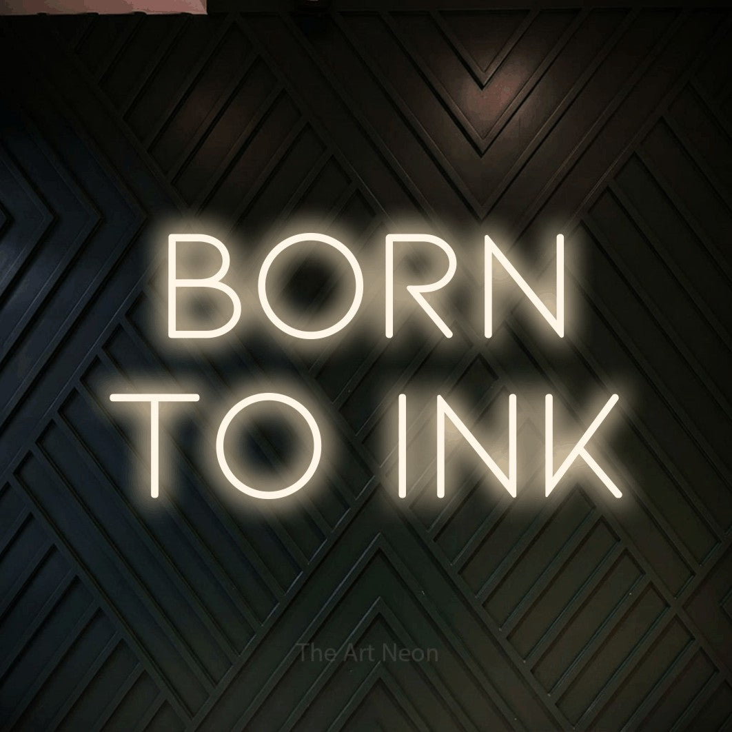Warm white LED neon sign reading "Born to Ink" against a dark geometric wood wall for tattoo studio décor