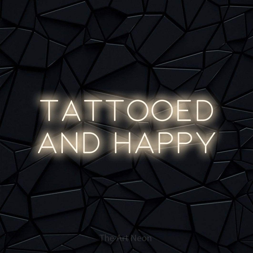 Warm white LED neon sign reading "Tattooed and Happy" against a black faceted wall for tattoo studio décor