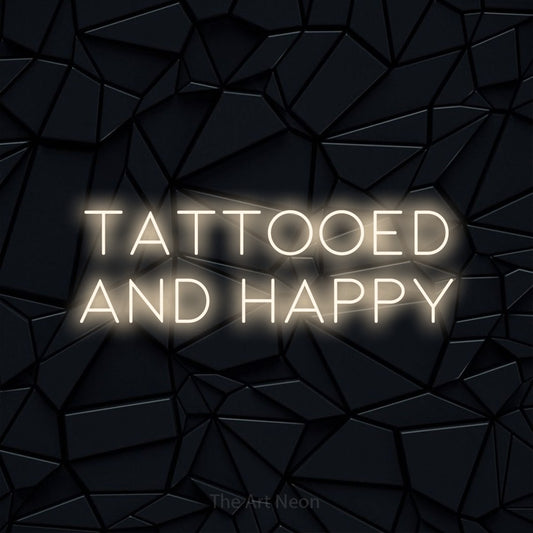 Warm white LED neon sign reading "Tattooed and Happy" against a black faceted wall for tattoo studio décor