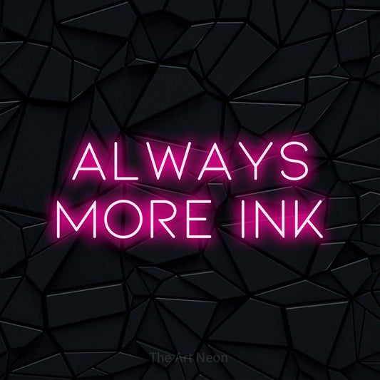 Hot pink LED neon sign reading "Always More Ink" against a black faceted wall for tattoo studio décor