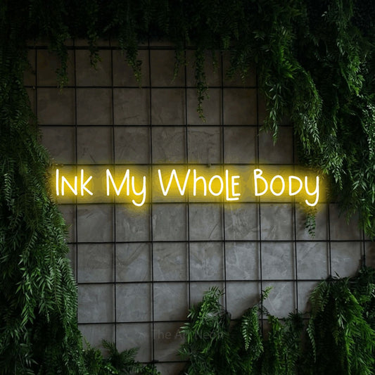 Yellow LED neon sign reading "Ink My Whole Body" against a green grid wall with foliage for tattoo studio décor