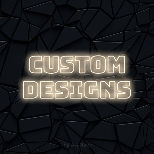 Warm white outline-style LED neon sign reading "Custom Designs" against a black faceted wall for tattoo studio décor