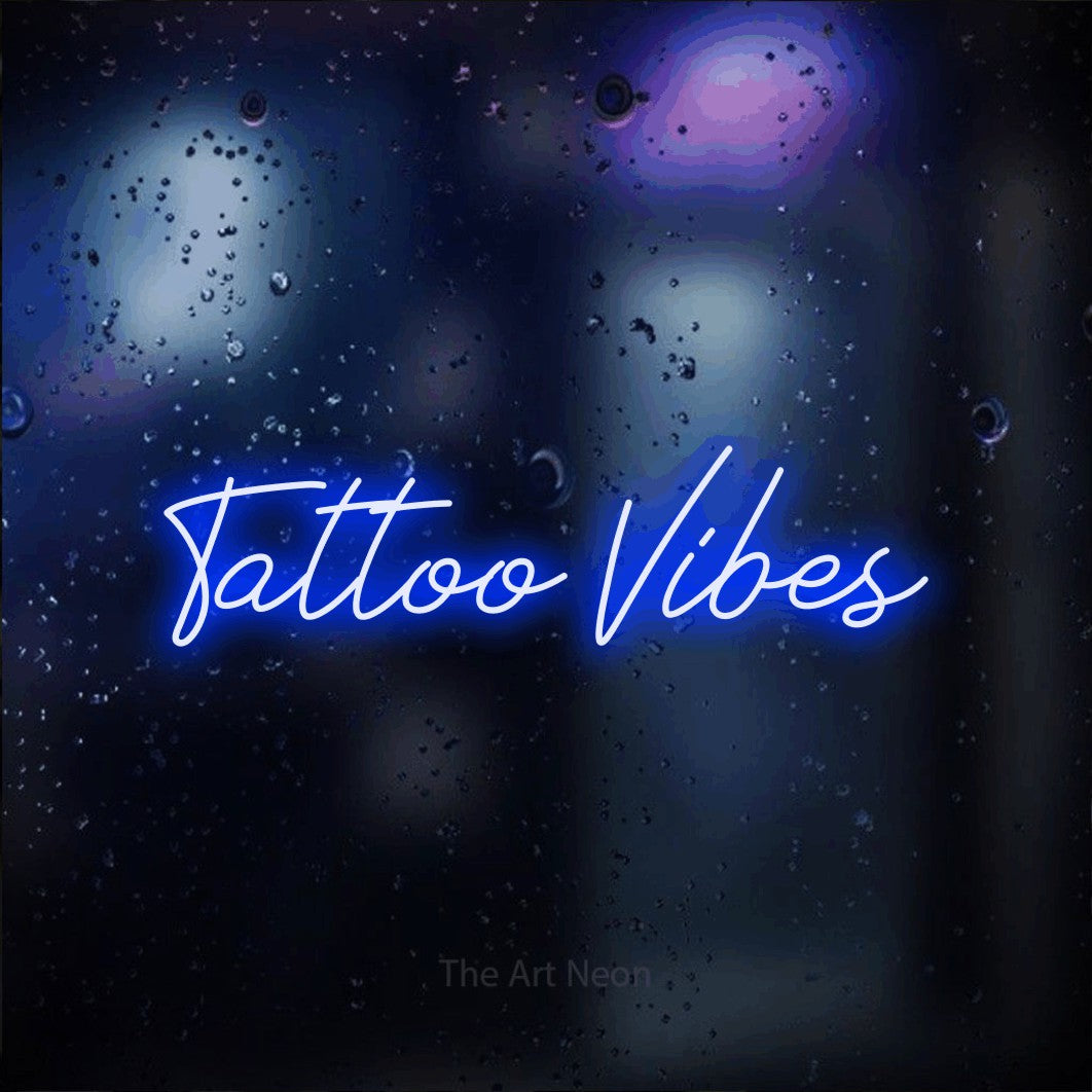 Enseigne néon à DEL à lumière bleue, de style manuscrit, affichant « Tattoo Vibes » sur un arrière-plan bokeh bleu foncé, pour décorer un studio de tatouage