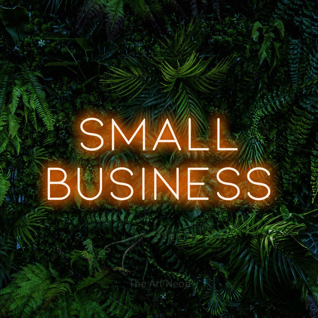 Orange LED neon sign reading "Small Business" against a dense tropical foliage wall
