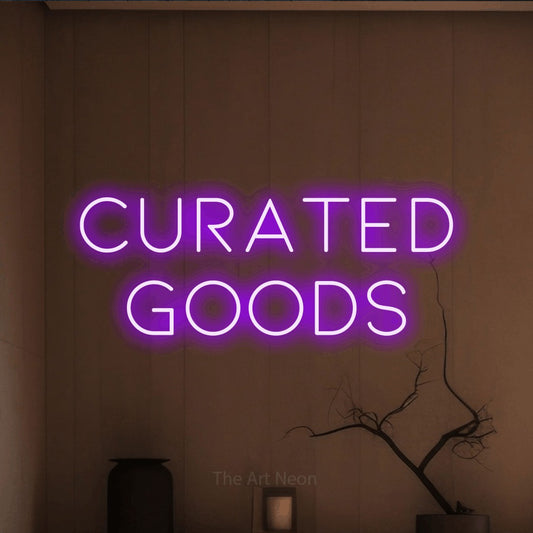 Purple LED neon sign reading "Curated Goods" against a warm brown wall