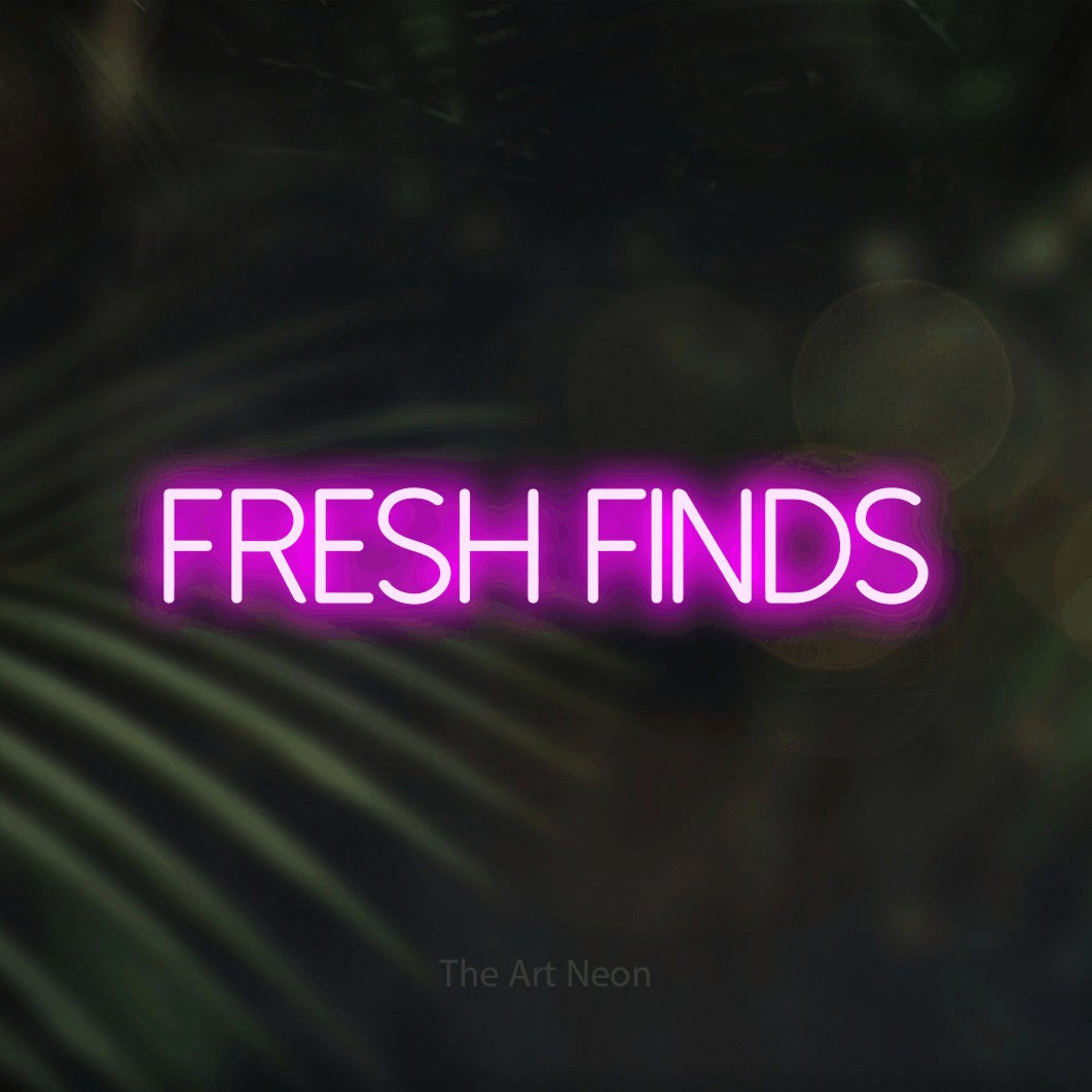 Pink LED neon sign reading "Fresh Finds" against dark blurred palm leaves