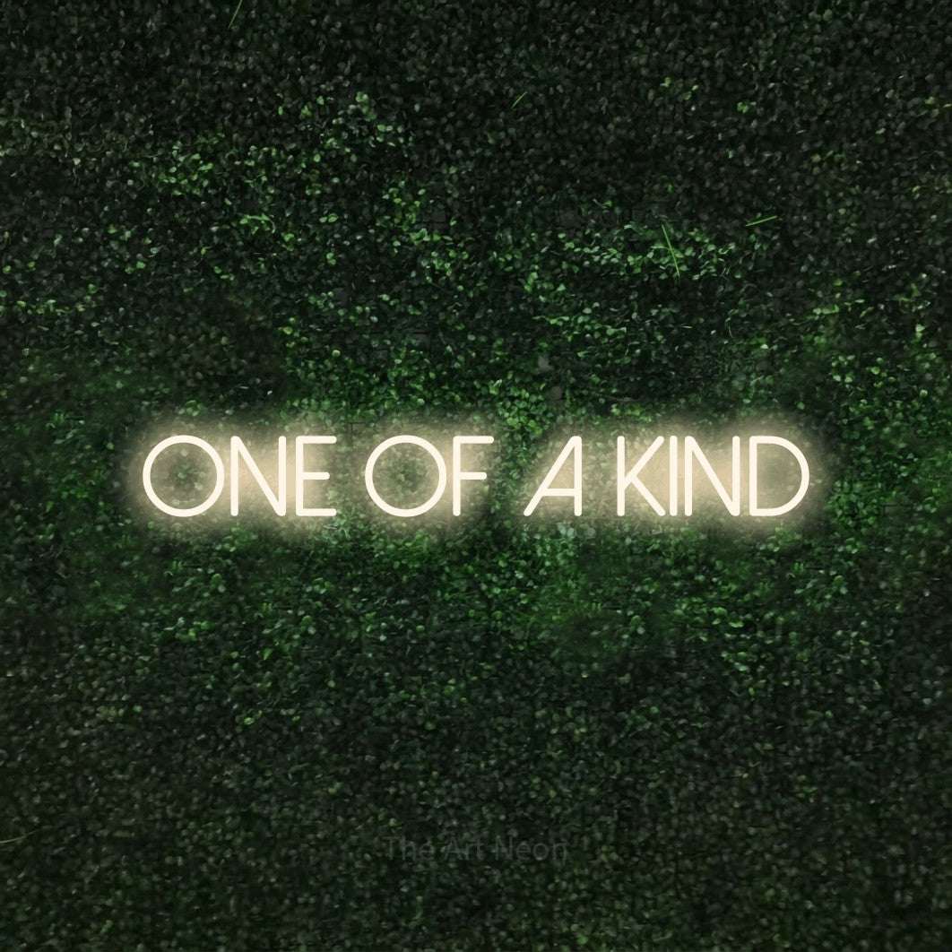 Warm white LED neon sign reading "One of a Kind" against a textured green moss wall