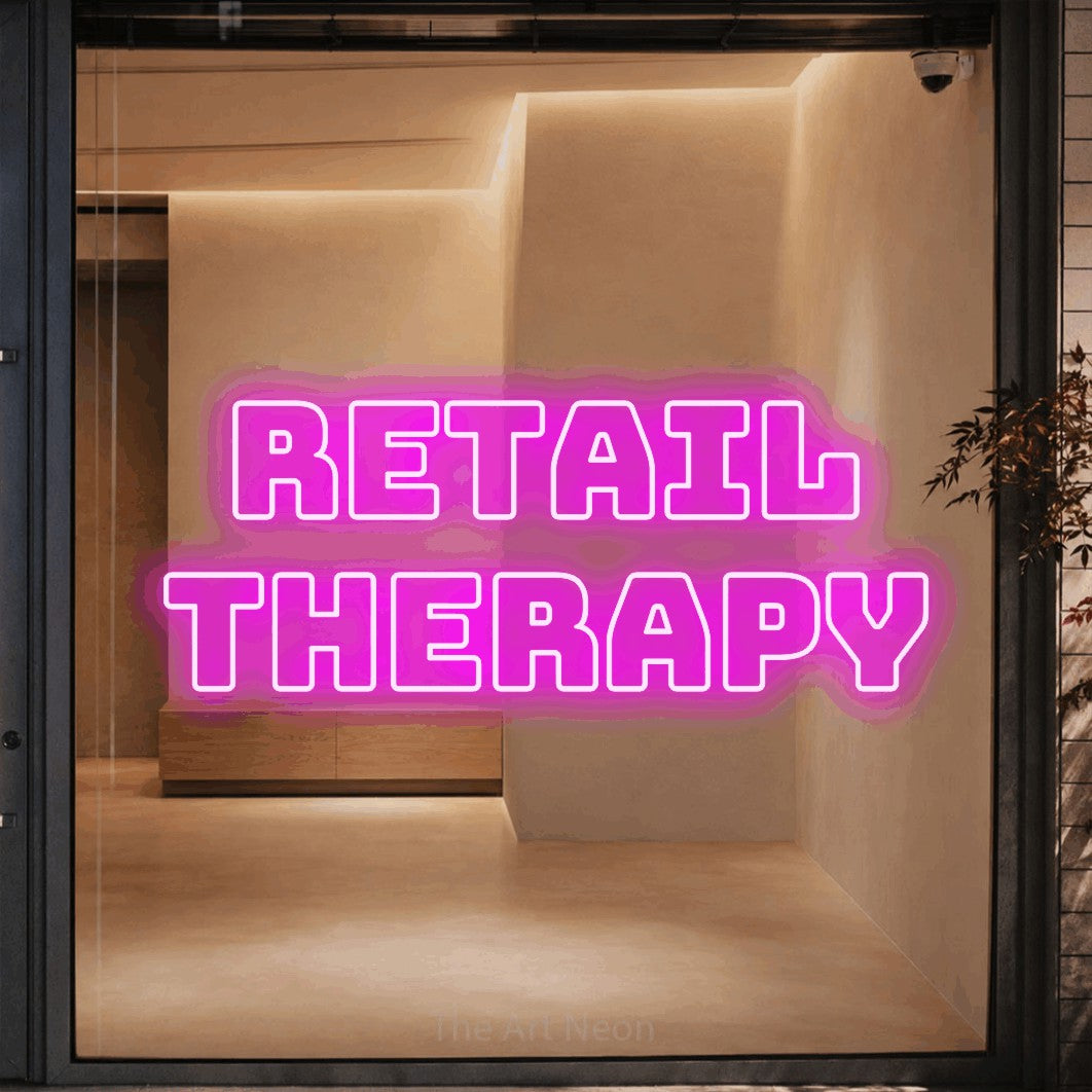 Pink outline-style LED neon sign reading "Retail Therapy" against a warm beige alcove wall