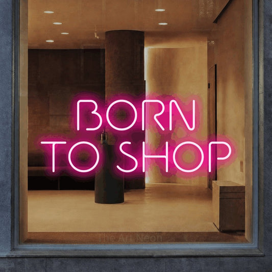 Hot pink LED neon sign reading "Born to Shop" in a warm modern interior