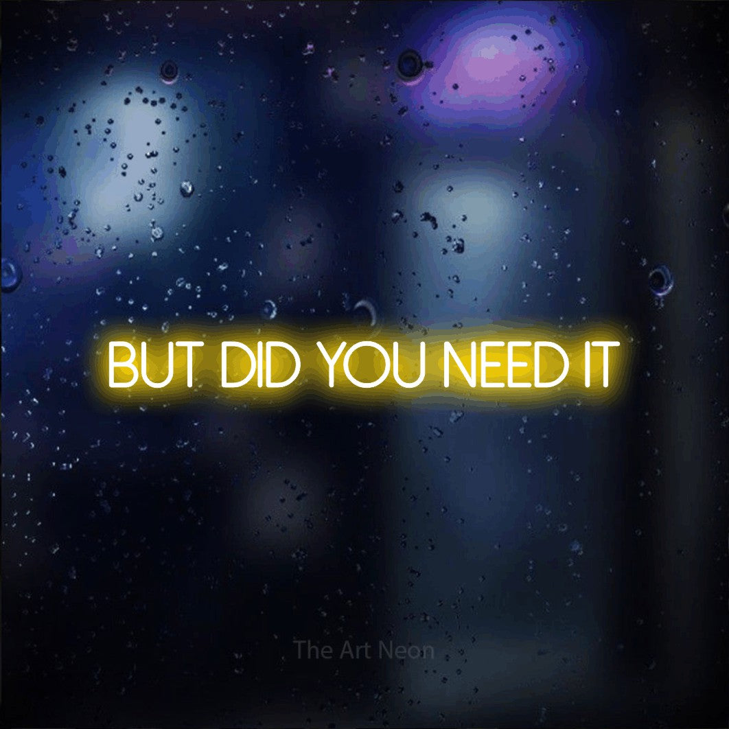 Yellow LED neon sign reading "But Did You Need It" against a dark blue bokeh background