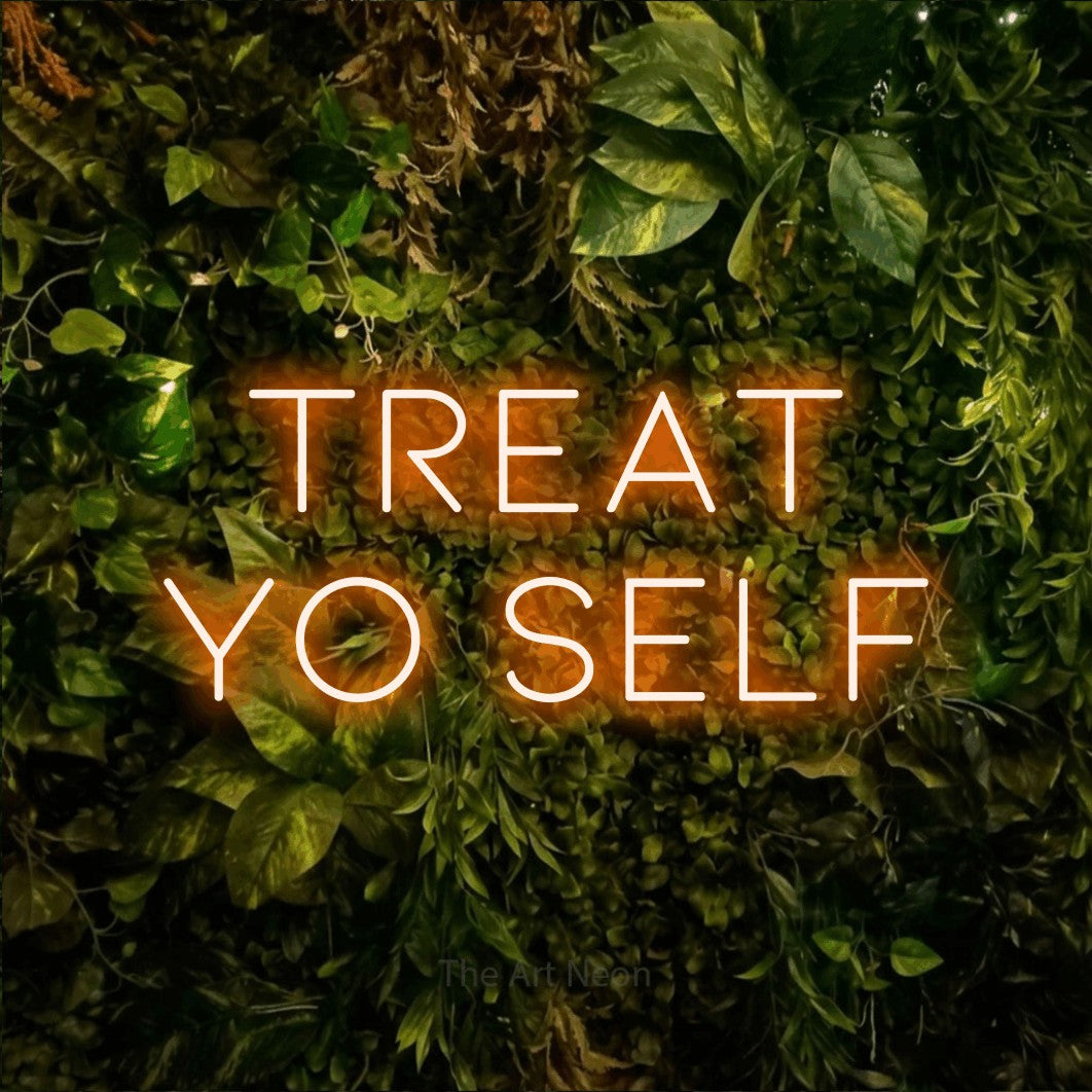 Orange LED neon sign reading "Treat Yo Self" against a textured moss and foliage wall