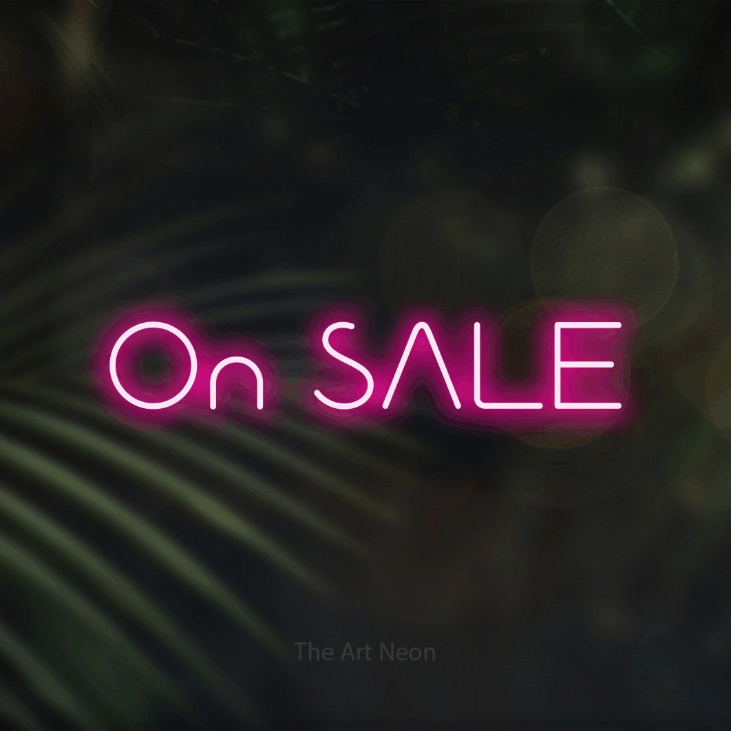 Hot pink LED neon sign reading "On Sale" against dark blurred palm leaves
