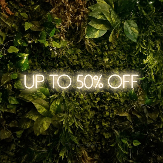 Warm white LED neon sign reading "Up to 50% Off" against a textured moss and foliage wall