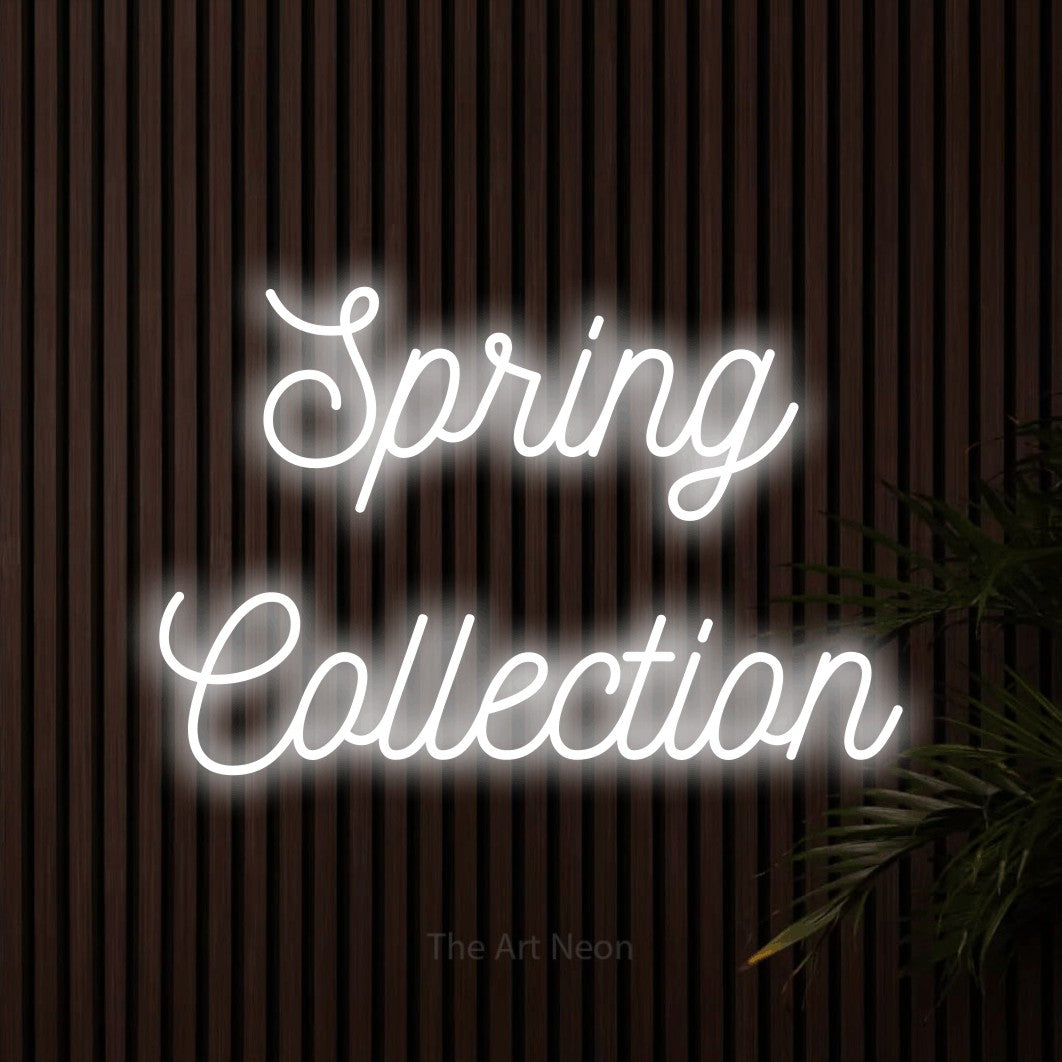 Cool white script-style LED neon sign reading "Spring Collection" against dark wooden slats