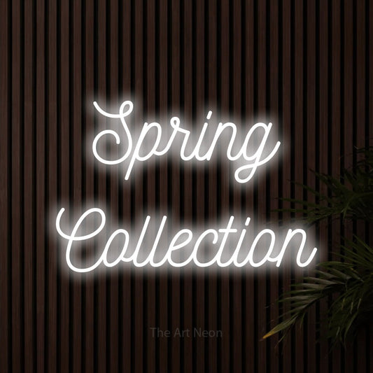 Cool white script-style LED neon sign reading "Spring Collection" against dark wooden slats