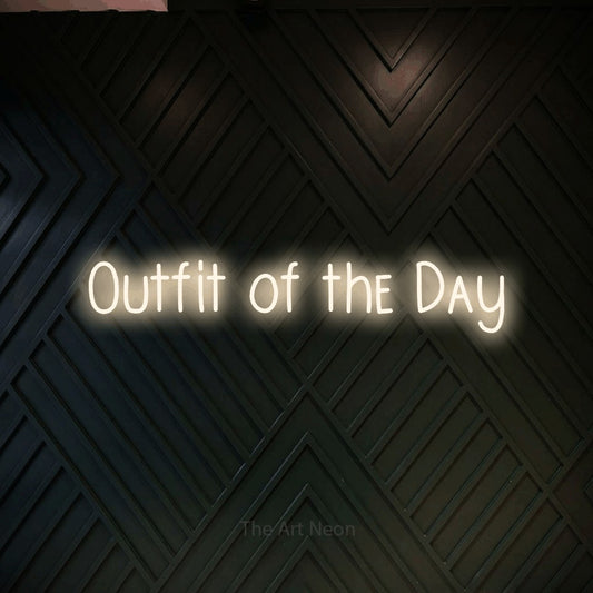Warm white LED neon sign reading "Outfit of the Day" against a dark geometric wood wall