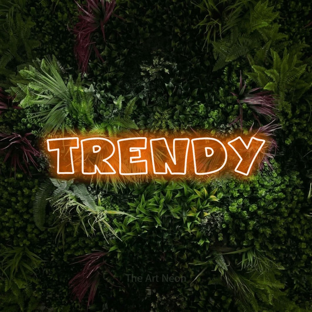 Orange outline-style LED neon sign reading "Trendy" against a lush garden wall with pink flowers