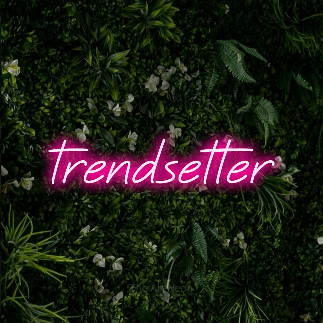 Hot pink LED neon sign reading "Trendsetter" against a leafy green wall