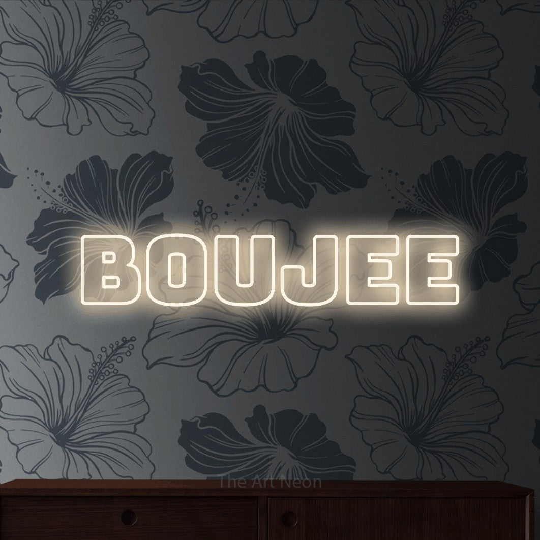 Warm white outline-style LED neon sign reading "Boujee" against grey floral wallpaper