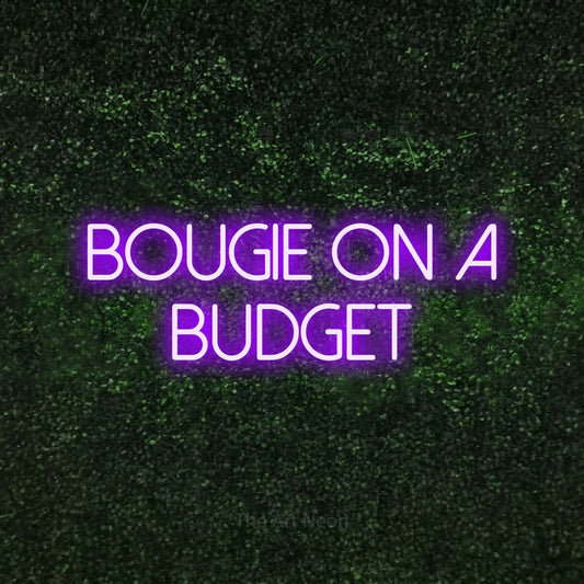Purple LED neon sign reading "Bougie on a Budget" against a textured green moss wall